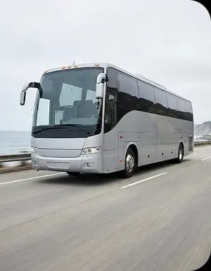 Silver coach on coastal road.